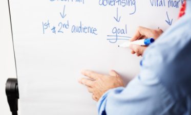 Businessman Writing Marketing Strategy on Whiteboard